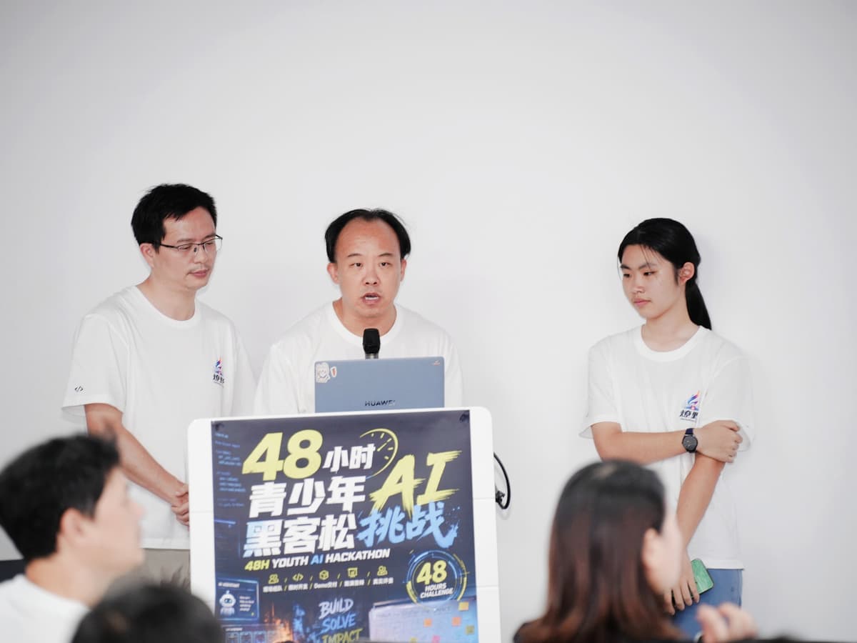深圳亲子 AI 黑客松路演:两位成年 Builder 和一位青少年 Builder 站在讲台前讲解项目